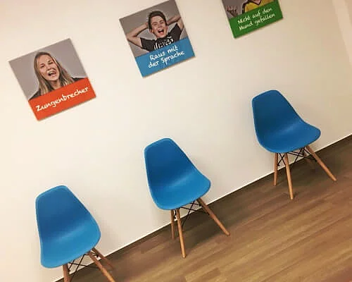 Warteraum mit blauen Stühlen und Bildern an der Wand