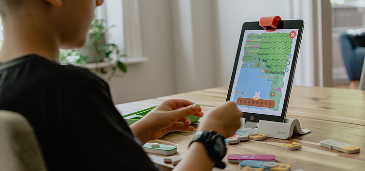 Ein Jugendlicher der auf ein logopädisches Spielgerät schaut.