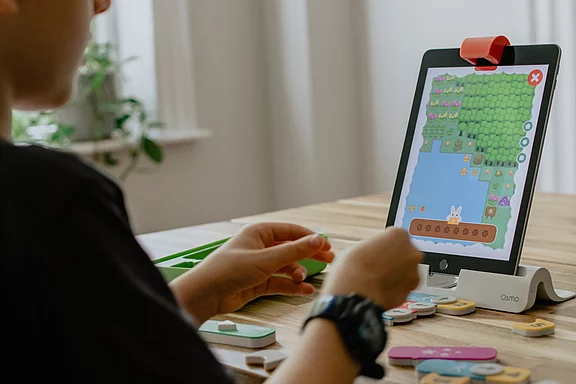 Ein Jugendlicher der auf ein logopädisches Spielgerät schaut.