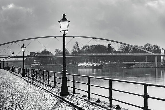 Sadie: Grau, Ein Bild mit Wasser und Brücke im Hintergrund.